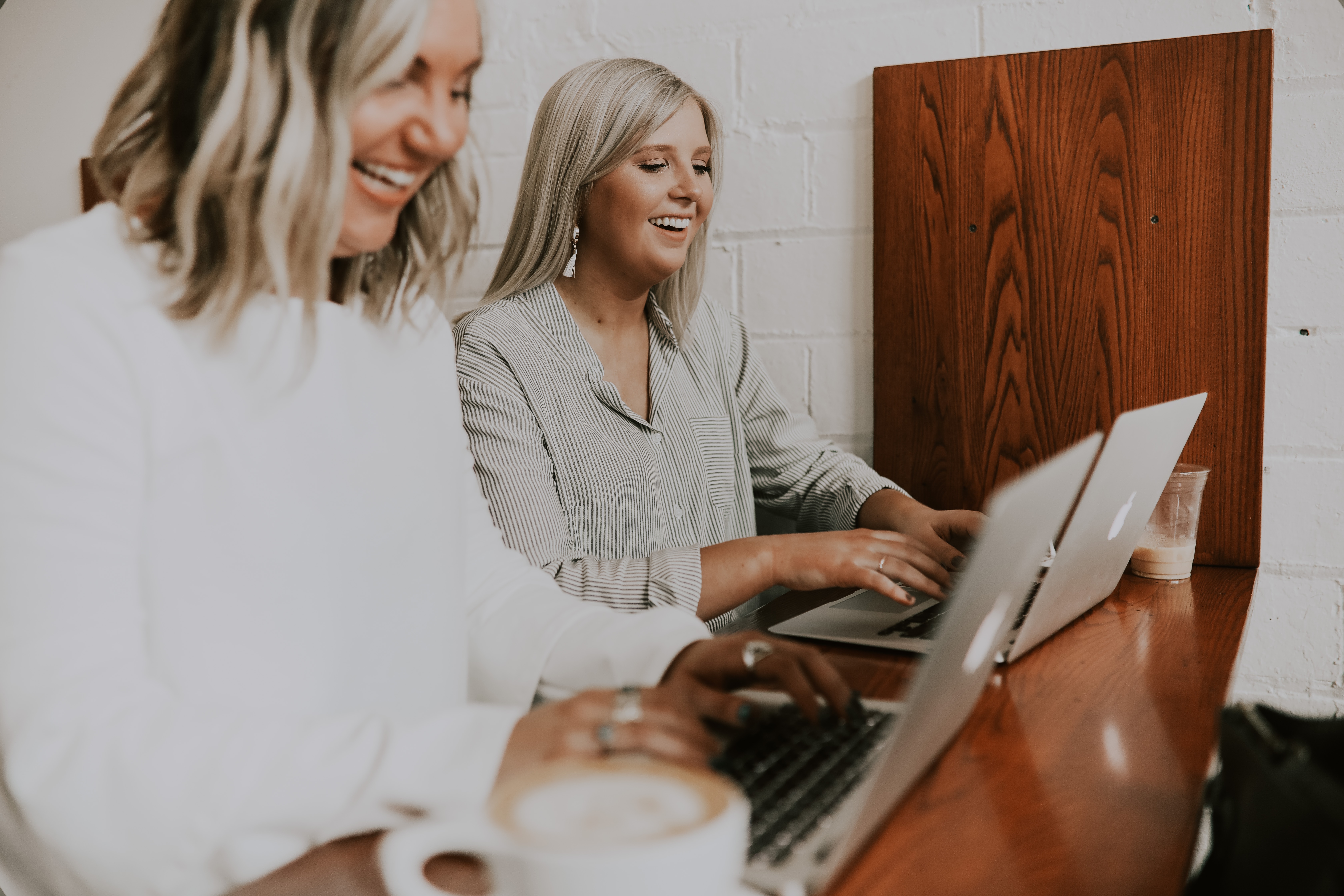 Two women smiling at computers