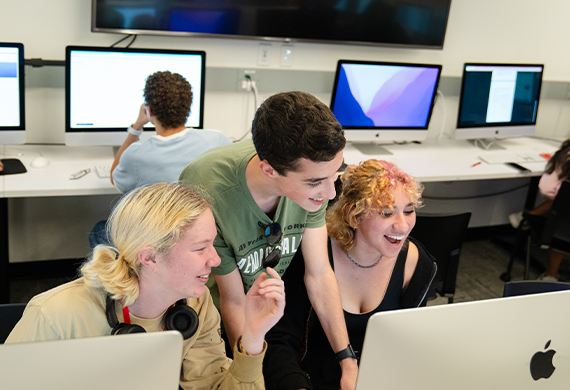 A group of students collaborating on a computer in a lab environment.