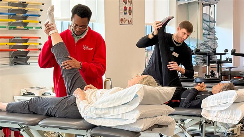 DPT students Cephas Ilevbare (left) and Larry Brown (right) engaging in a stretching clinic for local community members. Photo courtesy of Dr. Kristin Mende/Marist University.