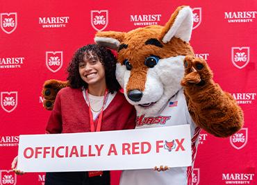 Image of Marist University student and Frankie Fox at Admitted Student Day holding a sign that says "officially a red fox."